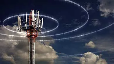 Telecommunications tower against a dark, cloudy sky, with white signal rings emanating from the top.