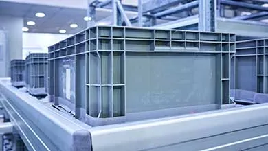 Gray plastic storage bins organized on metal warehouse shelving.