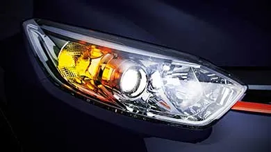 Close-up of a modern car headlight with the white main light and yellow turn signal both on.