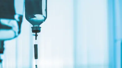 intravenous fluid bag hanging from a medical IV stand in a softly lit clinical room.