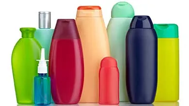 Eight colorful plastic bottles of varying shapes and sizes are arranged on a white background. The bottles are green, maroon, peach, light teal, navy blue, lime yellow, and pink, including designs such as tall cylinders, curved ergonomic bottles, and a small spray bottle with visible blue liquid.