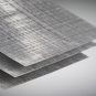 Close-up of three thin, gray composite sheets with a woven crosshatch texture, stacked.